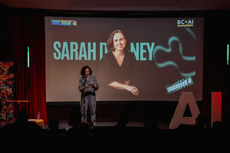Sarah presenting onstage with her title slide behind her.