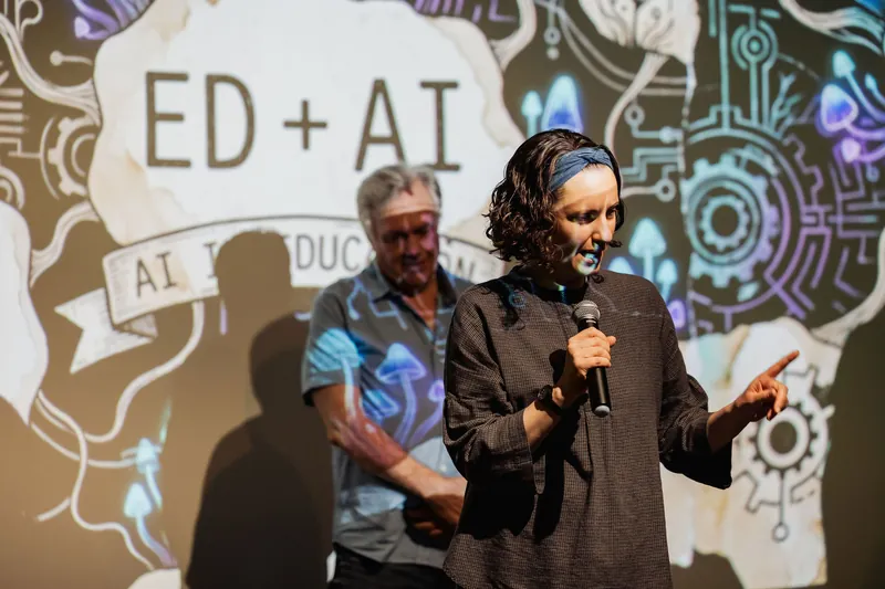 A presenter speaking in front of an AI education themed screen.