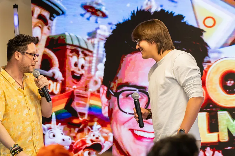 Host handoff and participant presentation beside a projected portrait, photo 171.