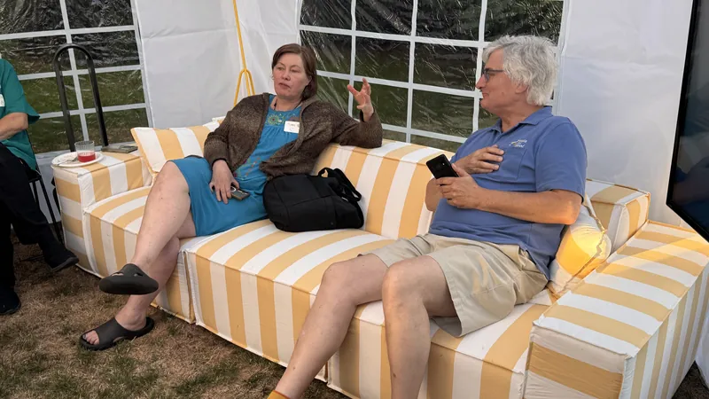 Guests talking on the striped sofa while the screen sits idle.