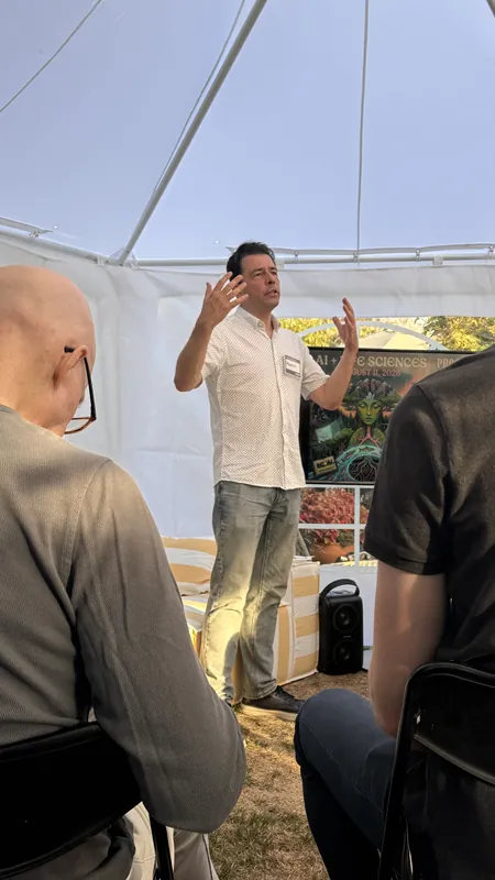 A speaker in front of the AI + Life Sciences August 11 poster.