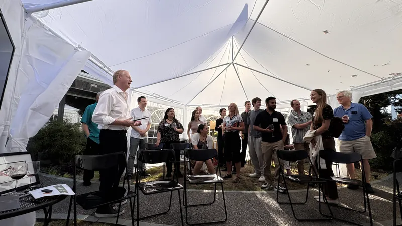 Attendees standing in mixed clusters inside the white tent.