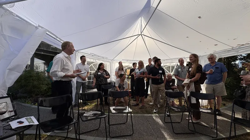 The tent room from mid-gathering, chairs and standing groups mixed together.