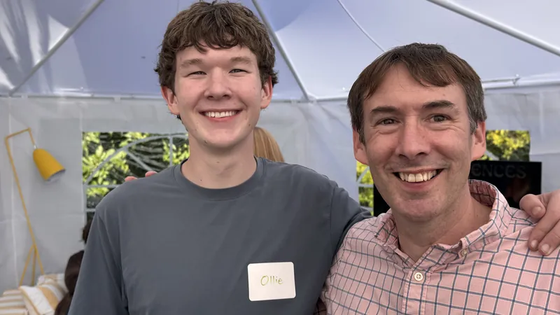 Two attendees smiling under the backyard tent as the August 11 meetup starts.
