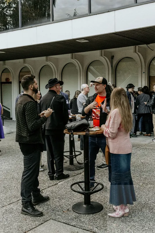Community members around a courtyard table. Photograph by Michelle Diamond, September 30, 2026.