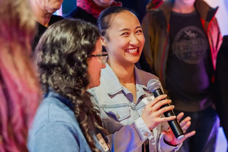 A smiling attendee speaking with the microphone during community Q&A.