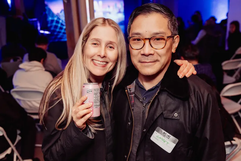 Two attendees smiling for a portrait in the audience area.