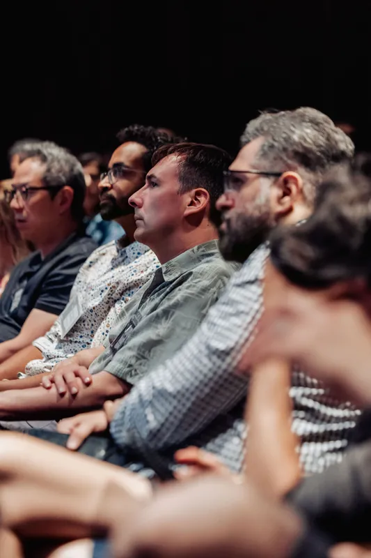 Rows of attendees lean in attentively as the indoor program unfolds in the planetarium theatre.
