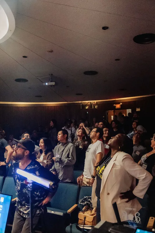 Dozens of attendees crane their necks upward, captivated by the spectacle unfolding above them in the planetarium.