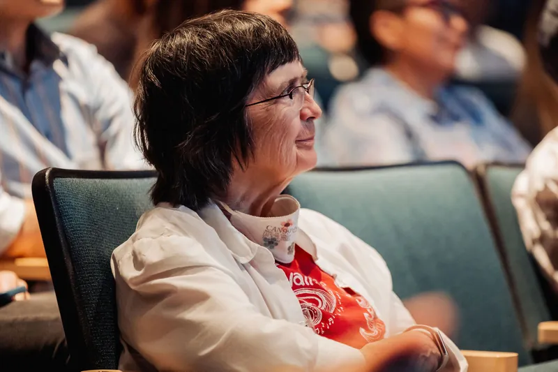 An audience member leans back with a quiet, thoughtful smile while taking in the evening program inside the Space Centre theater.
