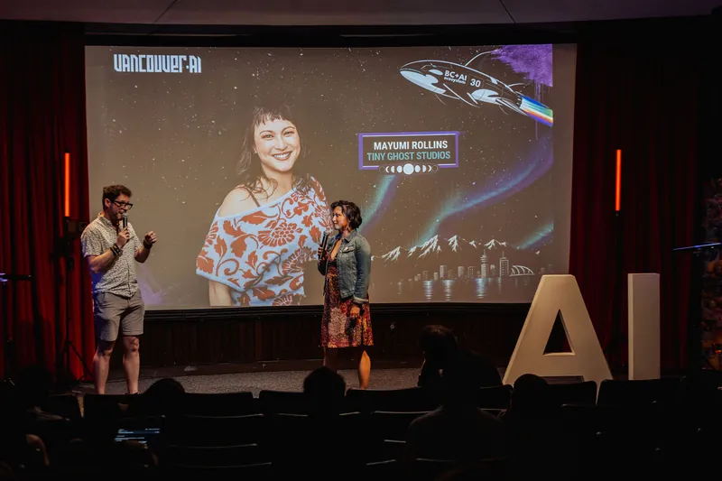A wide stage view shows the host and Mayumi Rollins in front of the Vancouver AI and BC+AI #30 branding, audience silhouetted below.