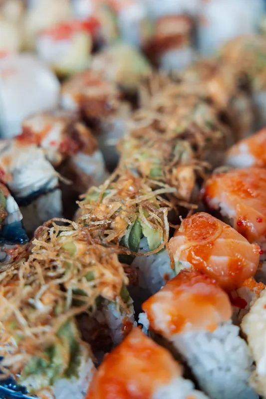 Specialty rolls topped with crispy shallots and spicy salmon sit ready for guests at the buffet.