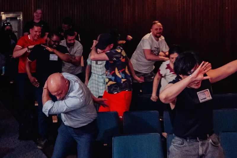 Attendees dab together in a burst of collective joy as the participatory dance sequence hits its stride.
