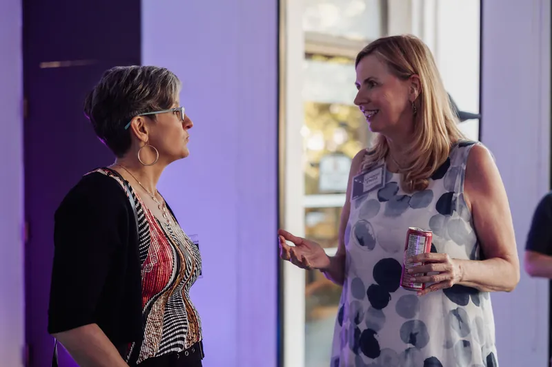 Two women share a lively exchange in front of the Space Centre's purple-lit interior walls.