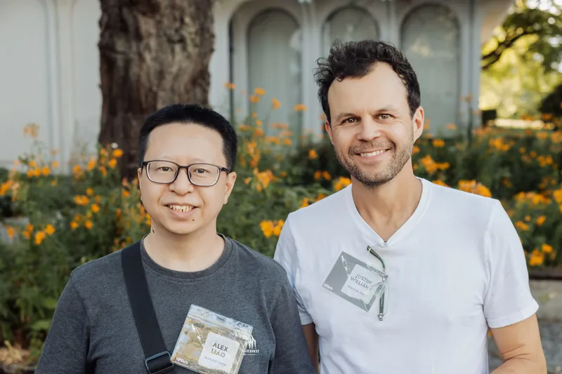 Two attendees smile together against a backdrop of orange marigolds during the golden-hour reception.