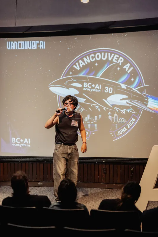The evening host stands before the Vancouver AI Mission 30 space-patch slide with the assembled crowd.