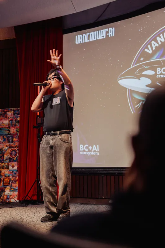 The performer raises a hand high while engaging the crowd beneath the BC+AI Ecosystem banner.