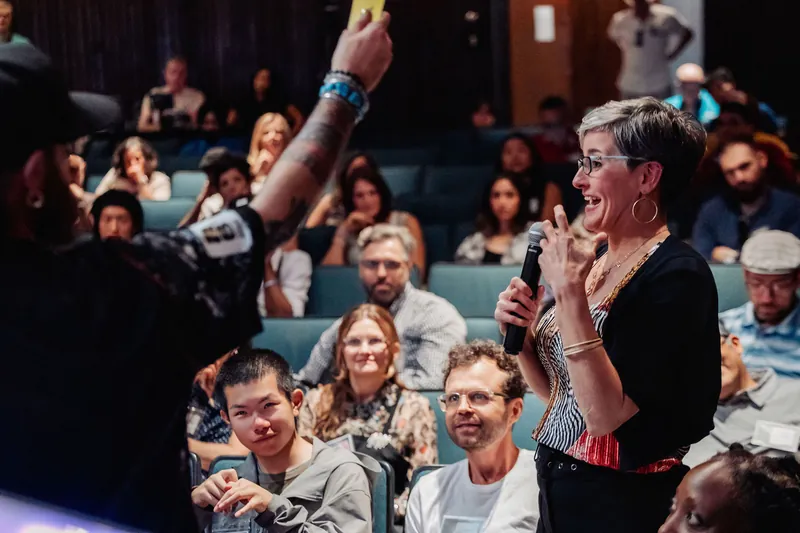 A spontaneous Q&A moment draws laughter from the crowd as the mic handler holds a yellow card aloft.