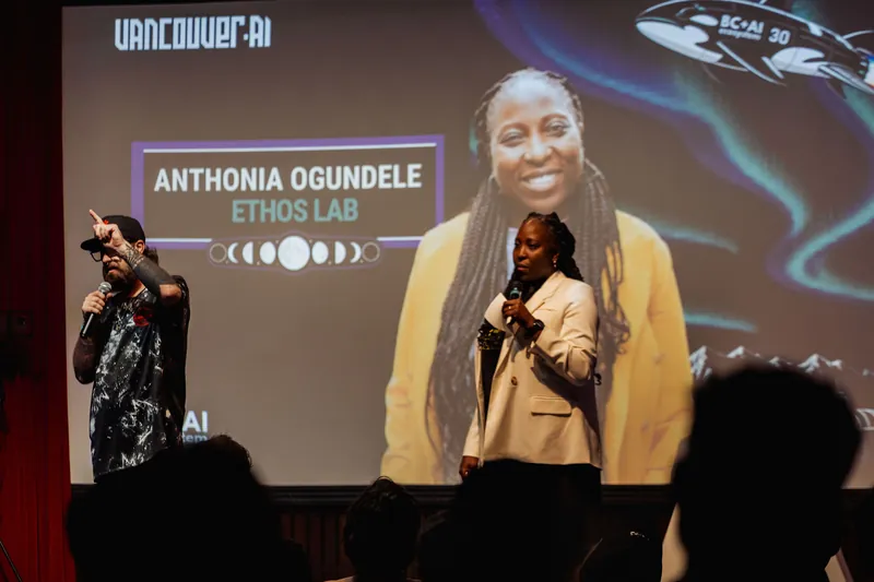 The host points skyward while introducing Anthonia Ogundele, whose speaker card dominates the stage screen.
