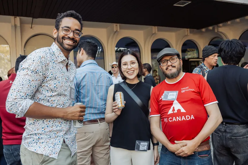 Three attendees — including one in a red HI Canada shirt — chat and laugh near the Space Centre entrance.