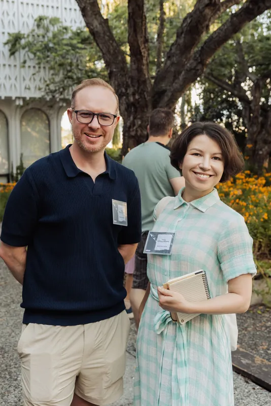 A pair of attendees share a warm moment in the Space Centre garden at golden hour, notebook in hand.