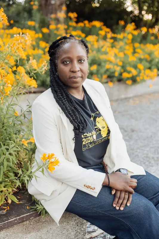 Seated beside a garden path, a woman in an Ethos Lab shirt rests quietly as dusk settles in.