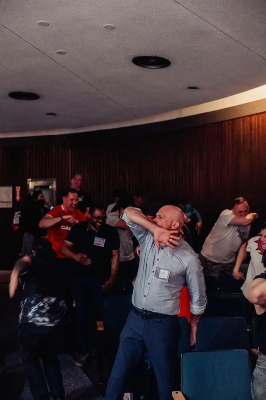 Laughter fills the room as the crowd follows along with an impromptu group dance in the planetarium hall.