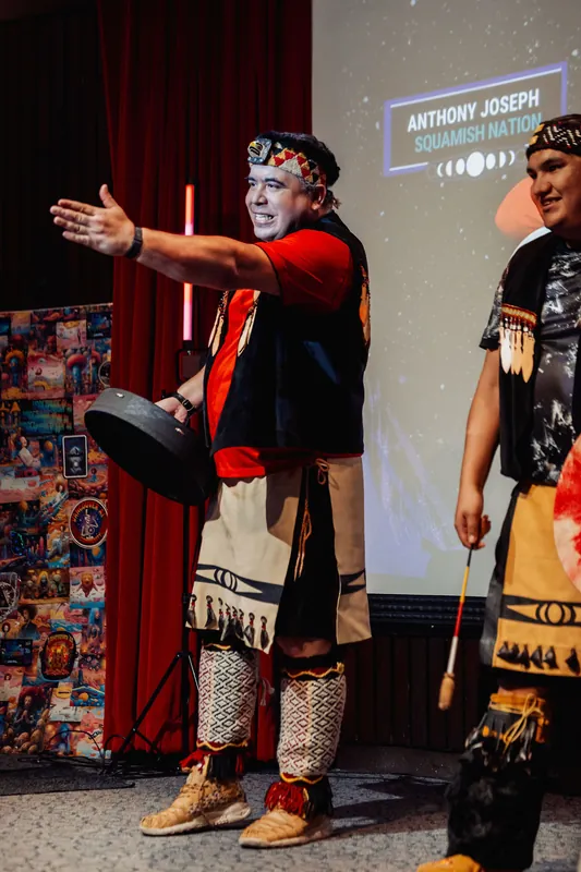 Anthony Joseph of Squamish Nation reaches his arm toward the audience during the welcome ceremony at the Space Centre.