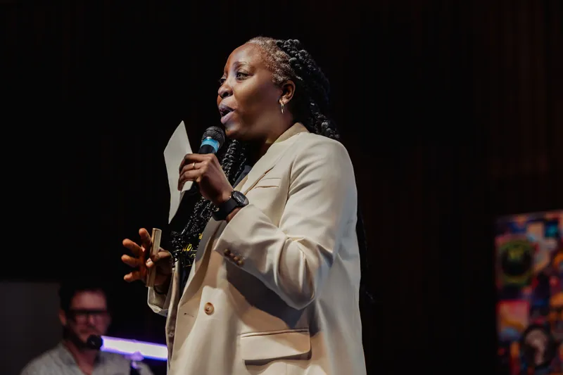 Anthonia Ogundele addresses the room from centre stage, notes in hand and voice carrying under the theater lights.