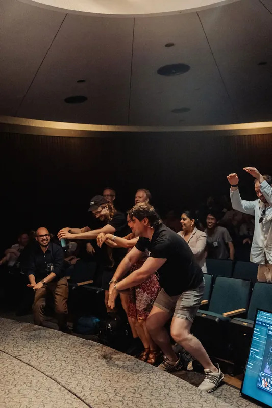 Attendees jump up to dance near the front row inside the dome as the opening ceremony spills joyfully into the crowd.