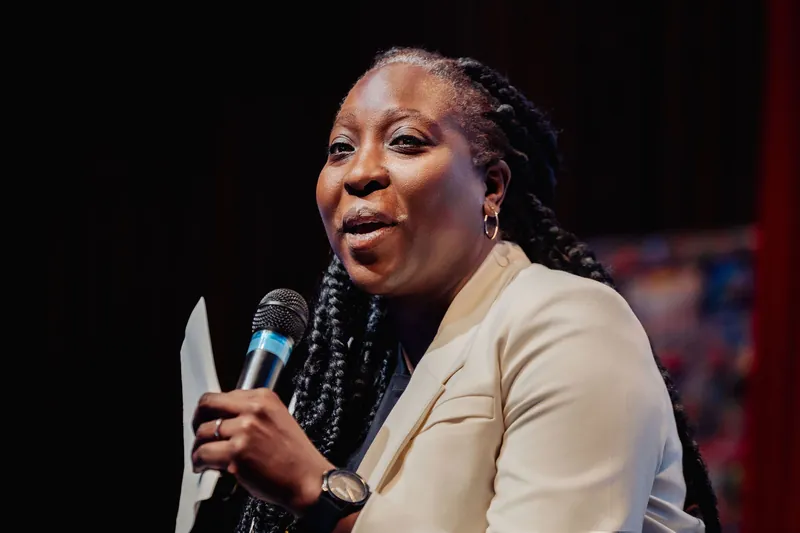 A close three-quarter portrait catches the full presence of Anthonia Ogundele mid-speech inside the Space Centre theater.