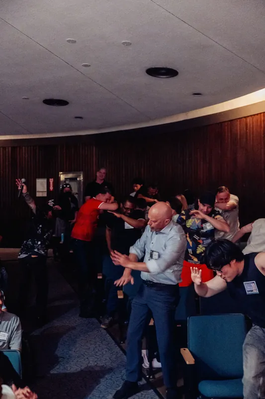 The group throws their arms wide in unison during a high-spirited moment of collective play inside the Space Centre.