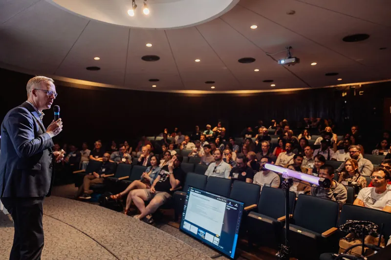 A speaker and the packed planetarium audience, seen from the side.