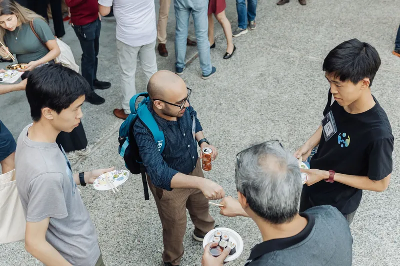 A small circle of attendees connects over food and drinks on the Space Centre plaza, seen from directly above.
