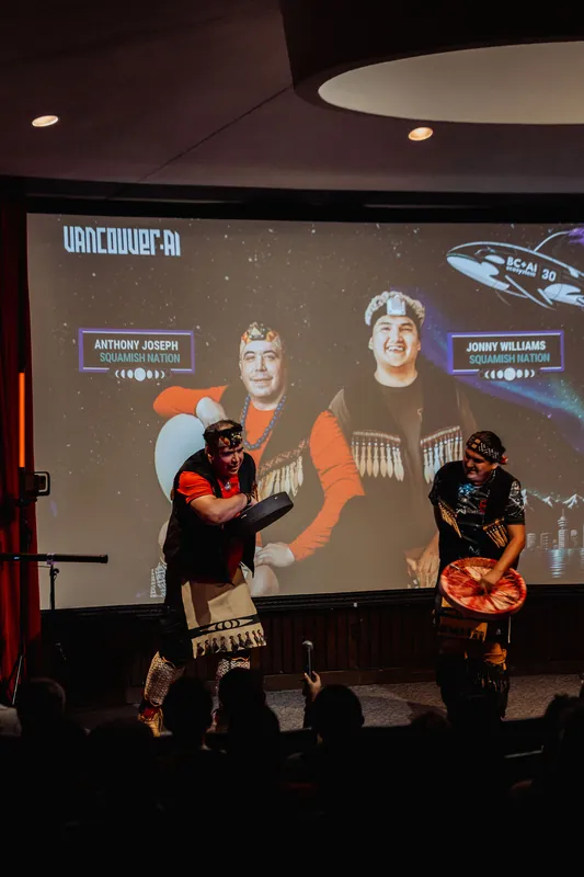 Anthony Joseph and Jonny Williams of Squamish Nation perform before a packed house under the Vancouver AI Meetup #30 title slide.