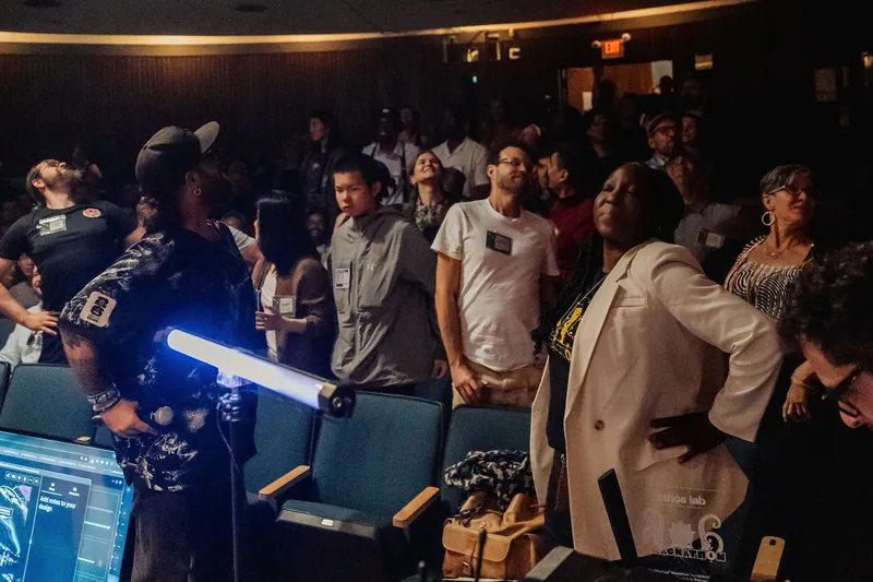A performer wielding a glowing blue light wand electrifies a packed crowd in the Space Centre theater.