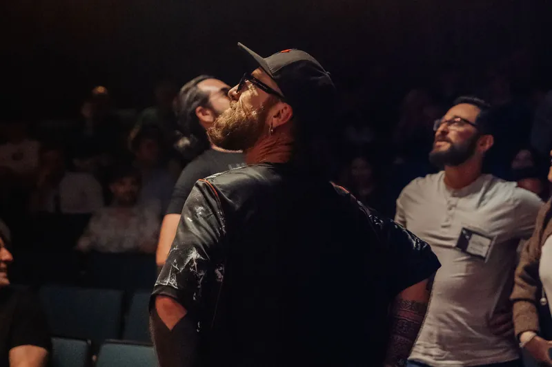 A bearded attendee gazes skyward in wonder, his face lit by the glow of the planetarium performance.