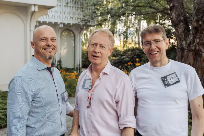 Three men share a spontaneous laugh on the outdoor plaza as the sun dips low behind the Space Centre.