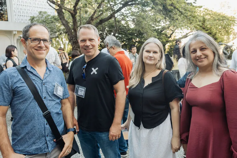 Four community members pose together during the outdoor reception as evening light warms the trees.