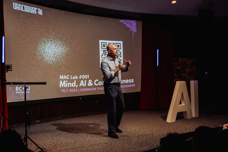 A speaker announces the upcoming Mind, AI and Consciousness MAC Lab from the stage beside bold letter props.