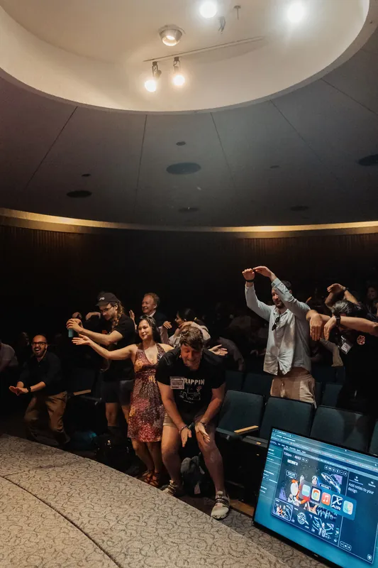 Audience members at Vancouver AI Meetup #30 dance and sway together inside the curved planetarium dome.