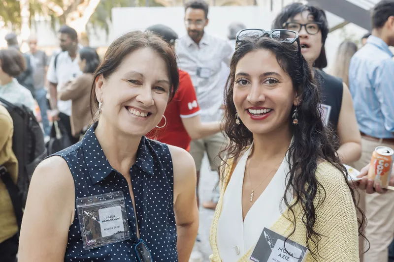 Two women smile at the camera amid the buzz of the outdoor pre-program reception at the Space Centre.