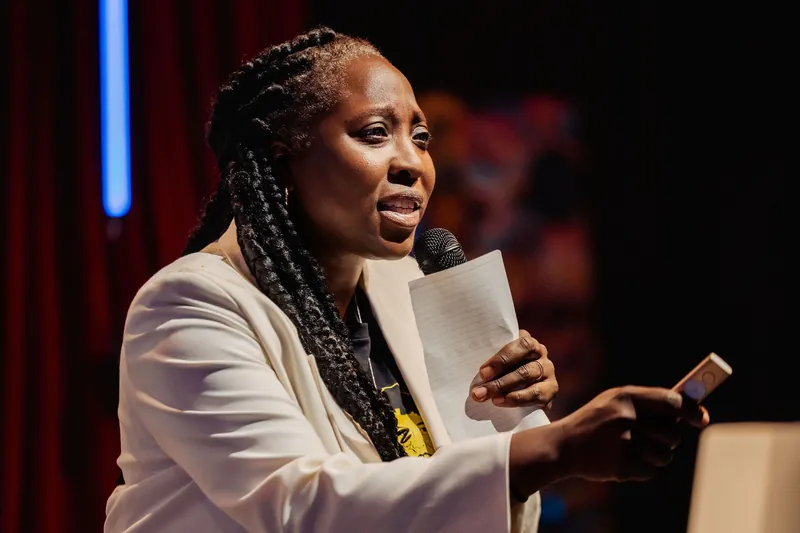 A tighter angle catches Anthonia Ogundele mid-sentence at the Space Centre program, mic raised as she holds her notes.