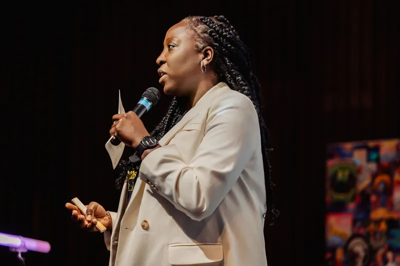 Anthonia Ogundele delivers her talk in profile, notes in hand, under warm stage lighting at the Space Centre.