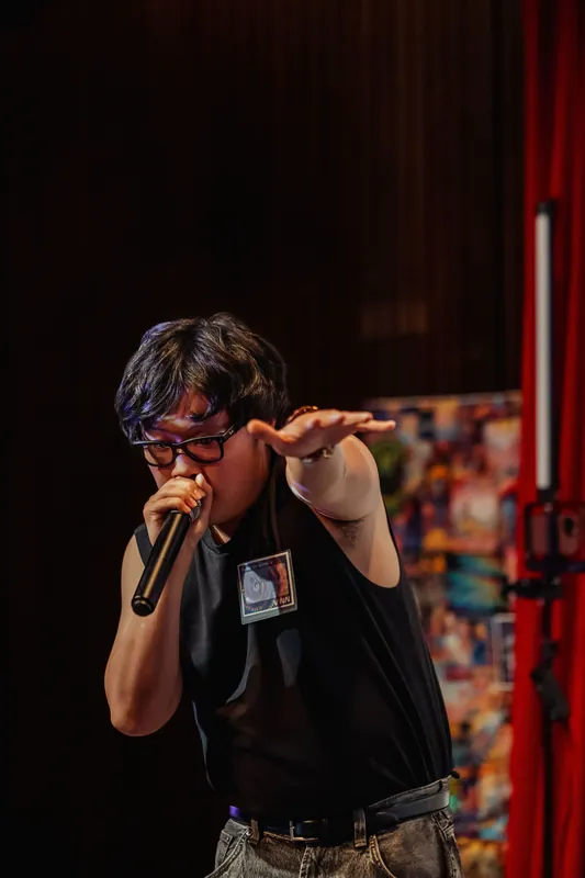 The MC leans into the mic with one arm slicing through the air, stage energy running high.