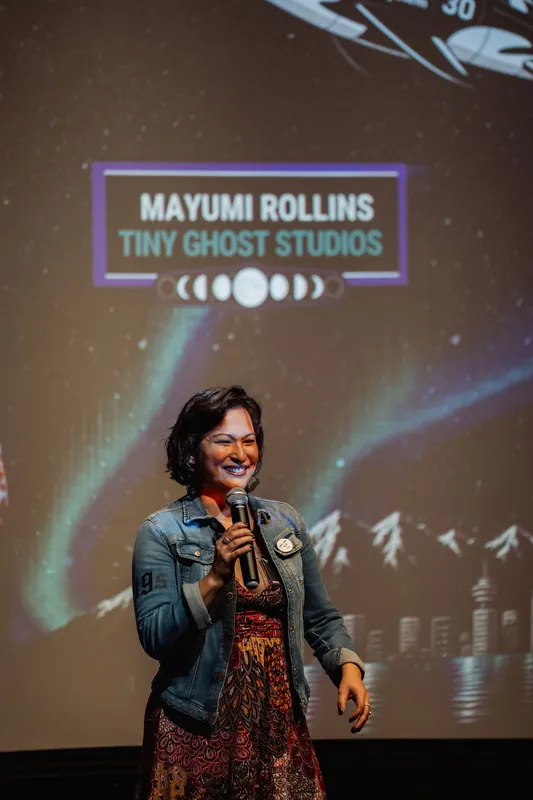 The performer wraps up a spirited set with a broad smile, mic raised in the darkened theater.