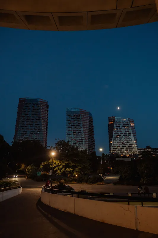 The Space Centre's curved roofline frames three glowing downtown Vancouver towers under a blue-hour moon after the event.