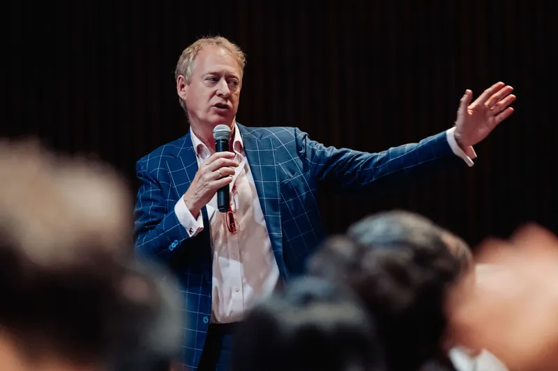 A speaker drives home an idea with a broad open-armed gesture on the auditorium floor.