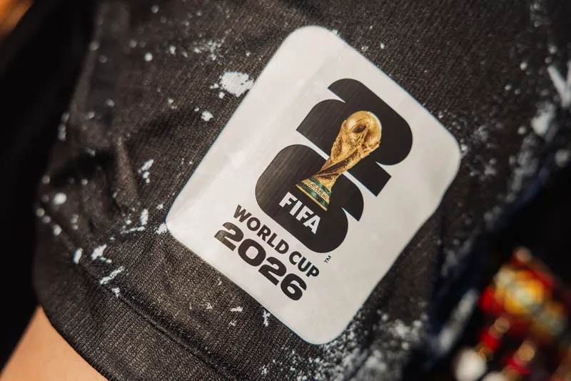 A FIFA World Cup 2026 badge dusted with white powder catches the eye on an attendee's shirt at the reception.