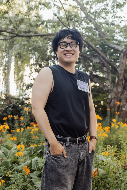A smiling attendee with an event badge poses among orange flowers at golden hour on the Space Centre plaza.